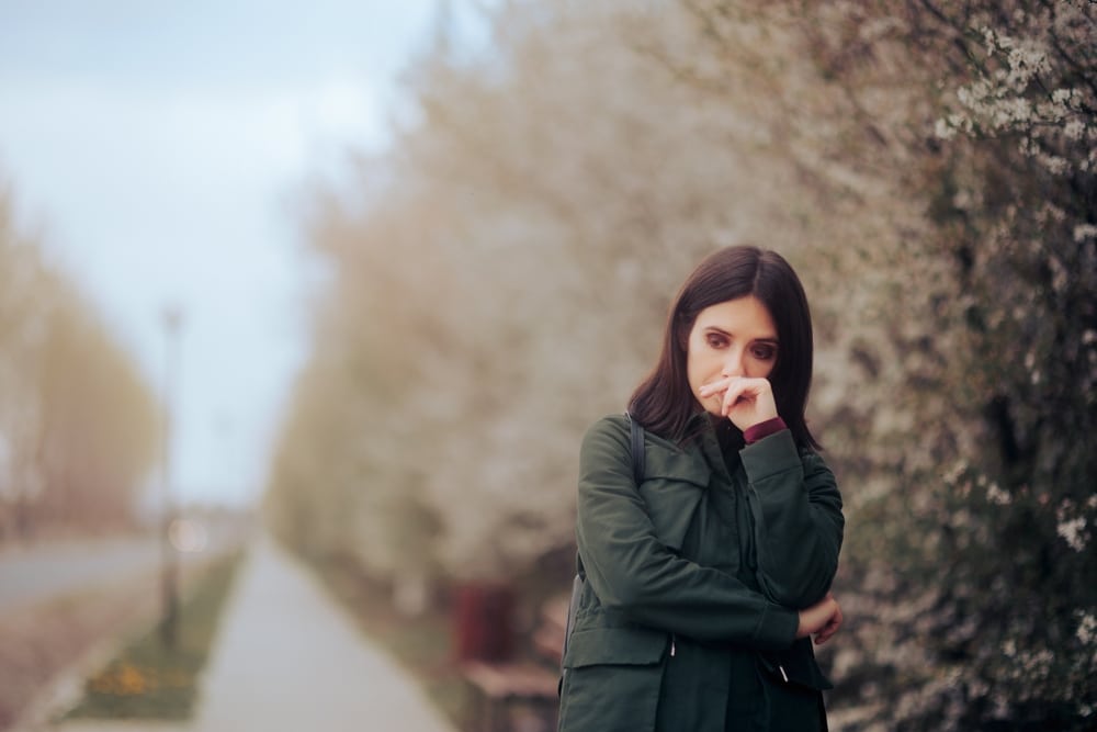 Unhappy woman walking outside due to depression, in need of therapy.