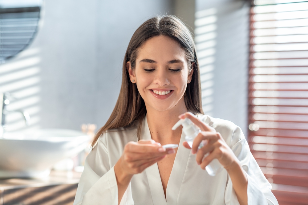 Happy woman about to apply moisturizer to her skin after Halo laser treatment.