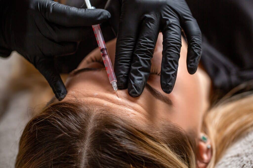 Patient receiving forehead filler injection from cosmetic specialist for wrinkle reduction