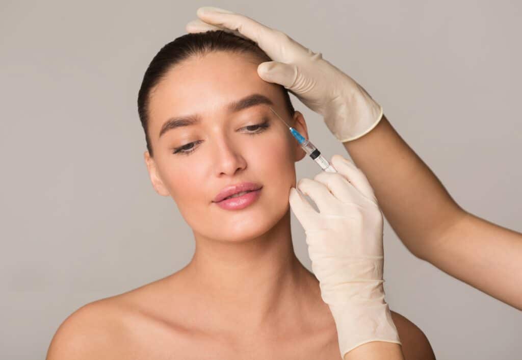 Young woman receiving Botox injection for wrinkle reduction, concept of plastic surgery, beauty enhancement, and anti-aging treatment in studio