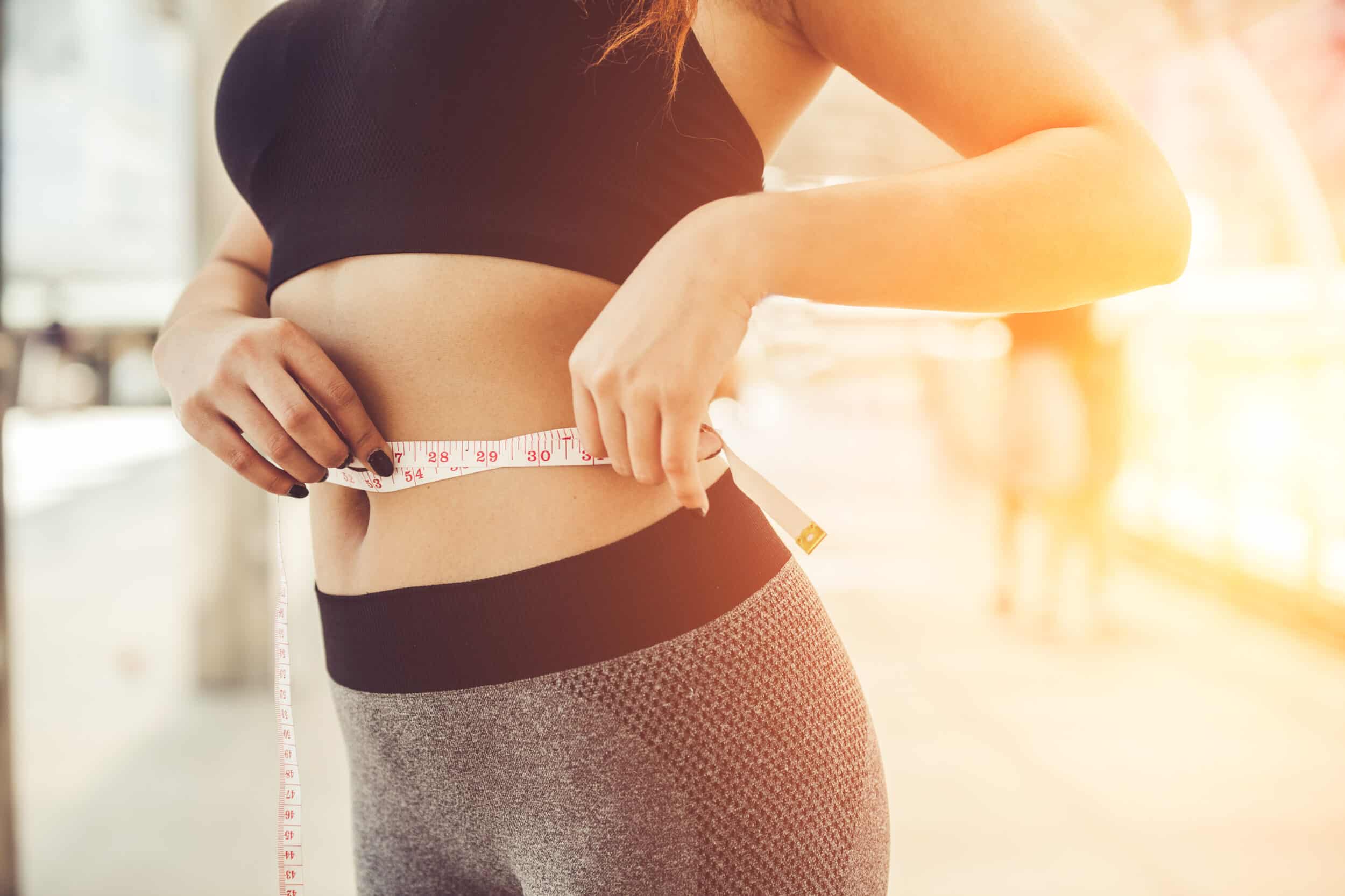Woman measuring her waist after losing weight with the help of semaglutide.